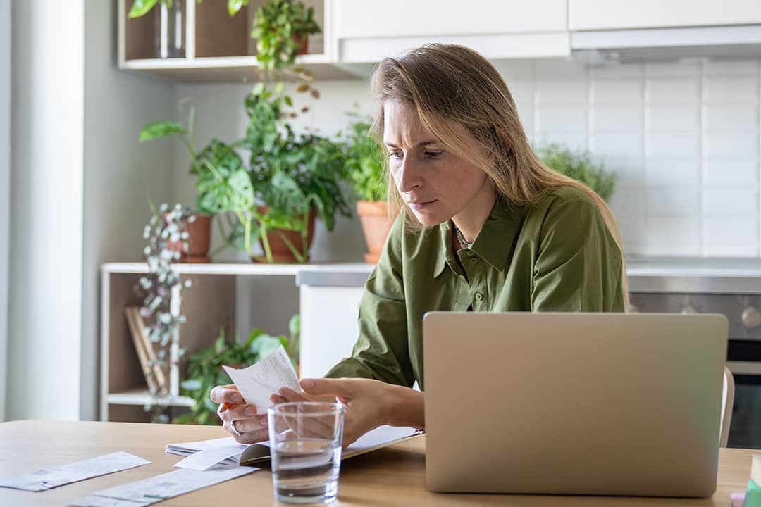 A person checking receipts and financial statements from different expenses at home.